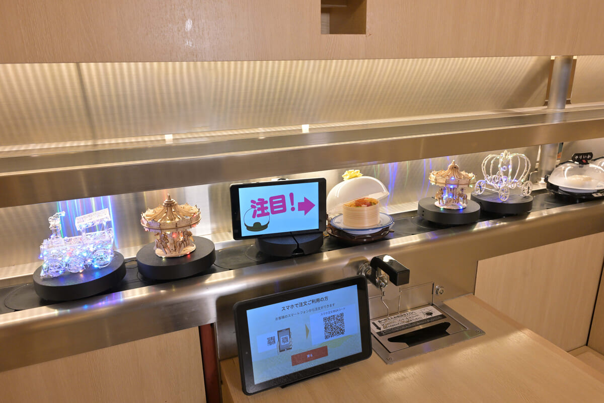 回転レーンから、パレードのように 輝く装飾と特別メニューが流れてくる