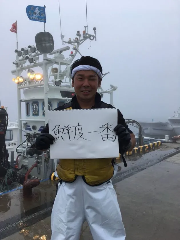 羅臼の漁港で鮮度一番のボードを持つ漁師