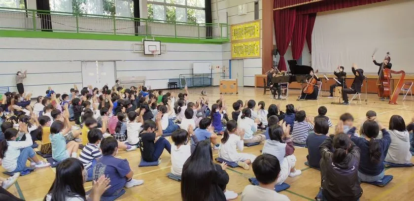 スクールコンサートで手を挙げて参加する児童たち
