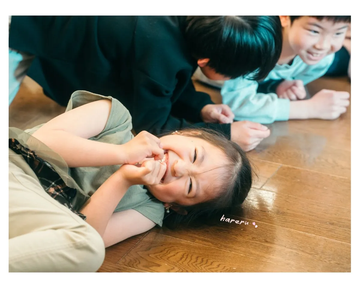 身体表現の遊びの中で床に寝転がって大笑いする女の子