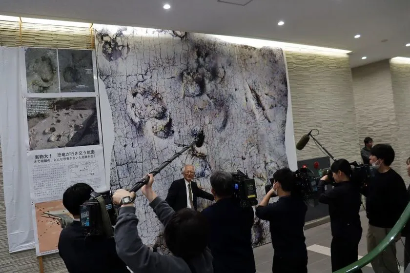 足跡化石の実物大写真の前で解説する石垣名誉館長