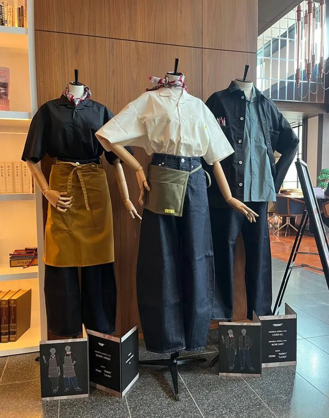 ハイアット セントリック 銀座 東京ロビーに展示された3体のマネキンによるYANUK&UNIVERSAL OVERALLコラボ制服全身コーディネート。左からエプロン付きF&Bスタッフ、デニムワイドパンツ×白シャツ×スカーフのフロントスタッフ