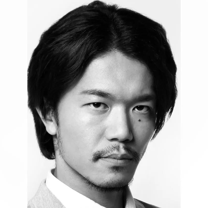 ひげをたくわえた男性の白黒プロフィール写真。スーツ姿でカメラを鋭く見据えるポートレートで、演出・宮尾俊太郎氏と思われる