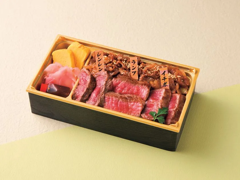 博多和牛弁当の商品写真。シンシン・ランプ・イチボの3部位ラベルが刺さった牛肉スライスがぎっしり詰まった黒塗り重箱で、隅に薩摩芋の煮物と紅生姜が添えられている