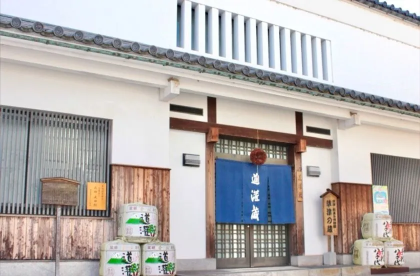 道灌蔵と書かれた暖簾が掛かる白壁の酒蔵正面玄関で、入口両脇に道灌銘柄の菰樽が積まれた外観写真