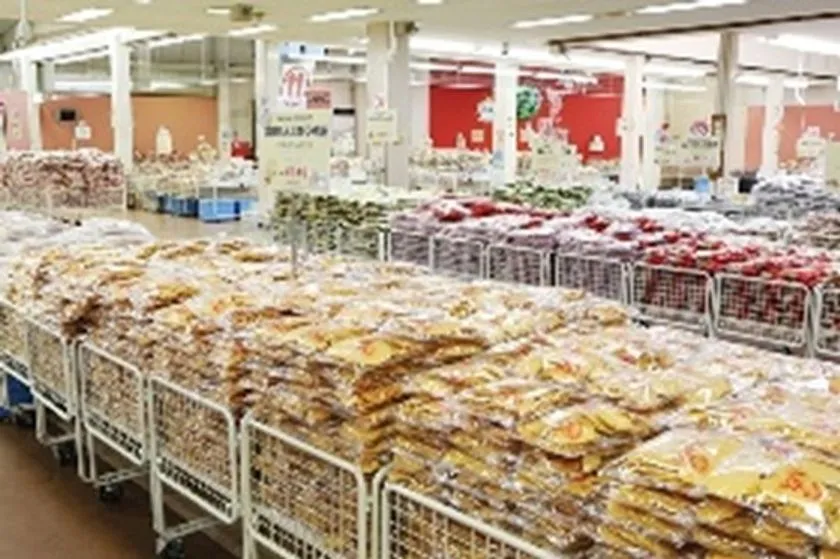 業務用スーパーまたは産直市場と見られる屋内売り場に菓子・乾物・袋詰め食品が大量にカゴ台車へ積まれた販売フロアの俯瞰ショット。知多半島の地元食品販売スポットとして参照可能な写真。