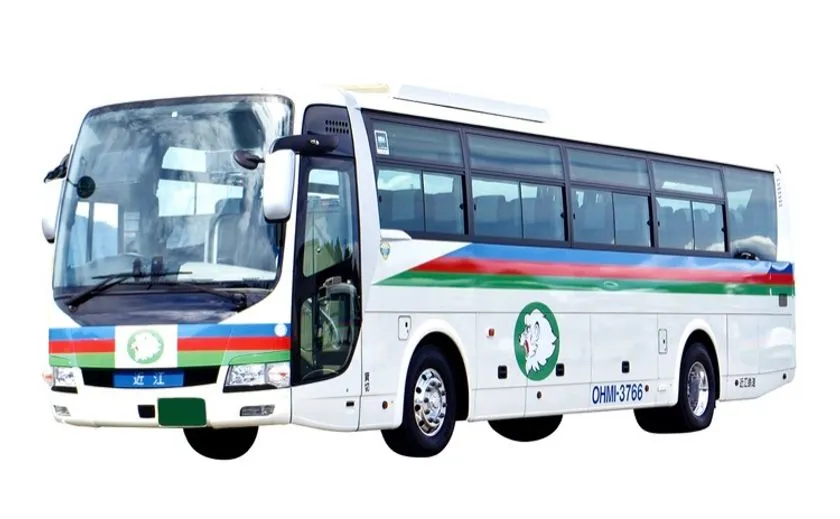 近江トラベル運行の観光バス(OHMI-3766)の側面・前面全景。白ボディに青・赤・緑のラインと近江のロゴが入った大型観光バス
