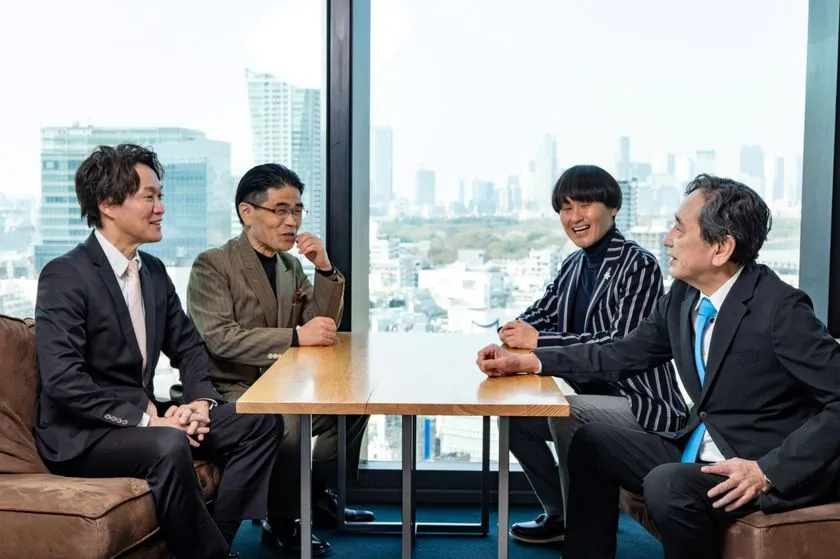 渋谷スクランブルスクエア高層階の会議室で、4名がテーブルを囲みながら談笑している対談全景写真。東京の高層ビル群が窓外に広がる