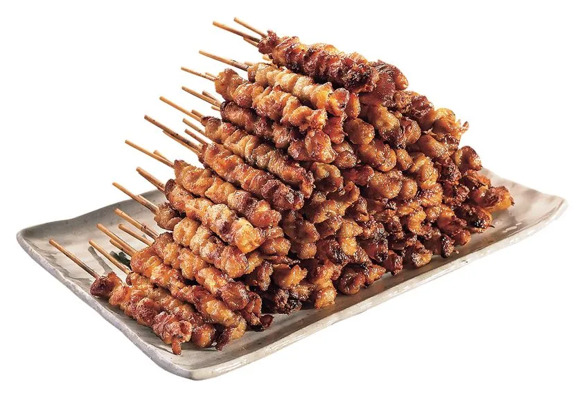 とりかわ串を数十本積み重ねて皿に盛った商品写真。こんがり焼き色のついた鶏皮串が山状に並び、博多の定番グルメとしての量感を示す