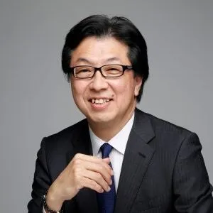 眼鏡をかけたスーツ姿の男性のプロフィール写真。グレー背景で笑顔、ATD-ICE 2026報告会の登壇者またはユームテクノロジー関係者の顔写真と思われる