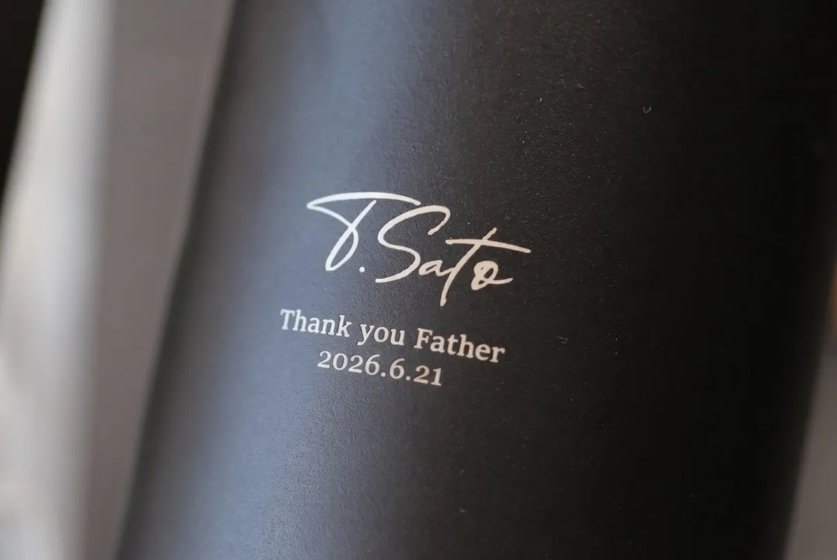 黒いタンブラー本体に白文字でサイン体の名前とThank you Father 2026.6.21の日付が刻印されたレーザー彫刻の名入れ加工クローズアップ