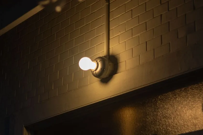 CAST ALUMINUM LAMPのブラケットライト点灯状態。レンガ壁面に取り付けられたアルミ鋳物製ソケットに電球が装着され、暗所での実使用イメージを示す