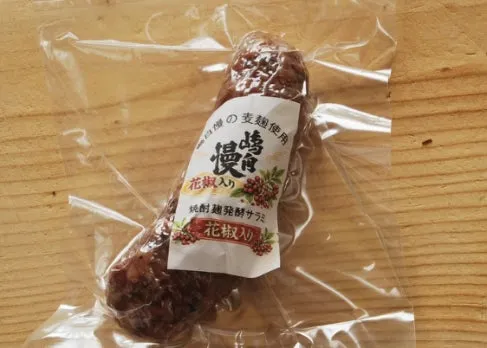 透明袋に真空パックされた花椒入り焼酎麹発酵サラミ1本。嶋自慢麦麹使用・花椒入り・純粋麹発酵サラミの商品ラベルが正面に貼付されたパッケージショット