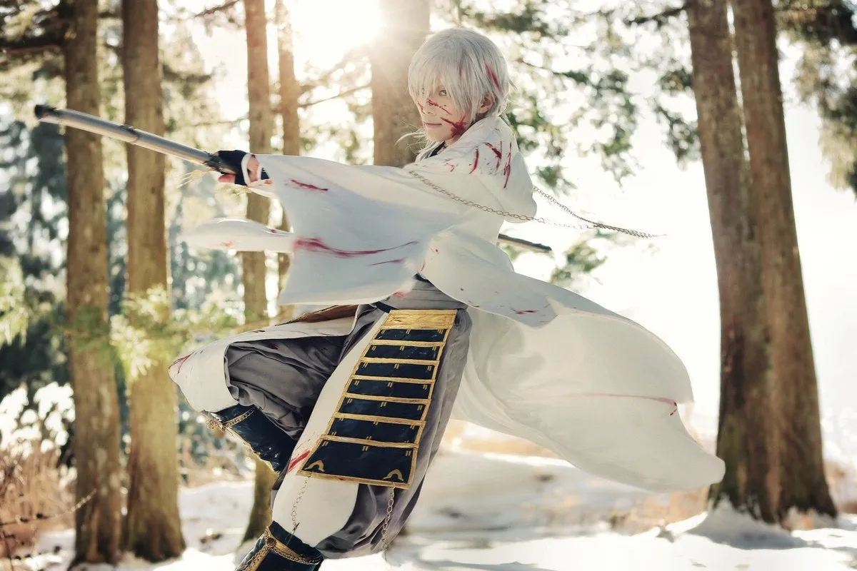 刀剣乱舞・鶴丸国永コスプレの白衣白髪キャラが雪上の杉林で刀を構えてジャンプするアクションポーズ。衣装に血しぶき表現あり、逆光の光差し込む構図