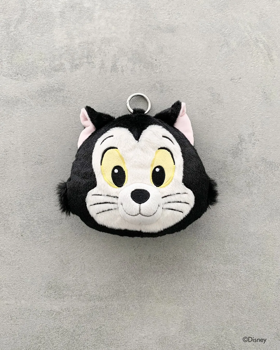ディズニー『ピノキオ』コラボの黒猫フィガロ顔型ぬいぐるみコインポーチ。黒×白のファー素材でフィガロの顔を立体的に再現し、リング付きの小物入れ