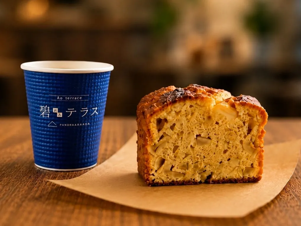 碧テラスロゴ入り紙カップと断面が見えるリンゴ入りパウンドケーキを木製テーブル上に並べた商品写真
