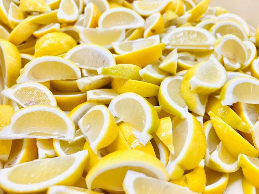琥珀糖の原料となる国産レモンをくし形にカットして大量に並べた素材ショット。果肉の黄色と白い内皮のコントラストが前面に出た製造工程を示す俯瞰写真