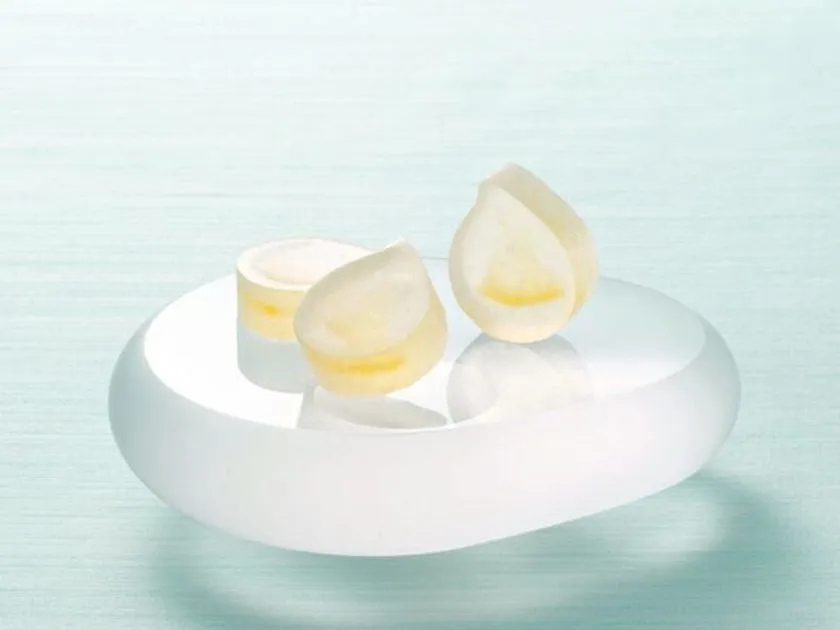 琥珀糖「レモンの雫」2個を白い丸皿に乗せた商品アップショット。水滴形の半透明白×レモンイエローの断面が確認できる