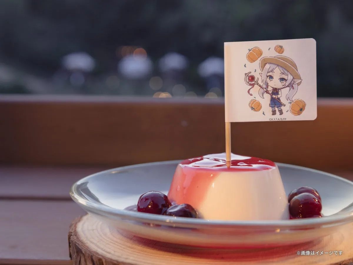 メルクーアプリン1個を屋外テラスで撮影した単体カット。フリーレンのちびキャラ旗が正面向きで大きく見え、背景は夕暮れの木立ちボケ。ガラス皿と木製コースターの組み合わせが確認できる