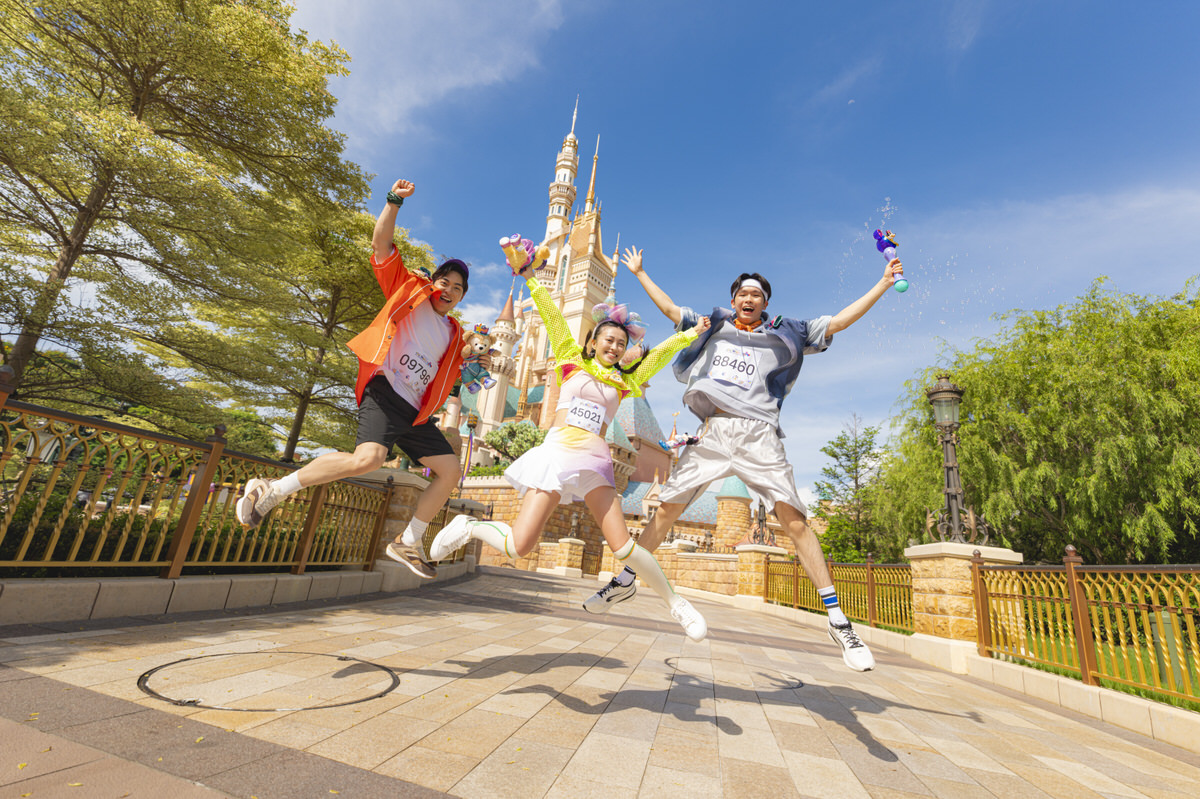 香港ディズニーランドの城の前でジャンプするランナーたち
