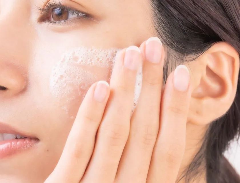 女性の頬に白い泡状の化粧水を指で広げている使用イメージ