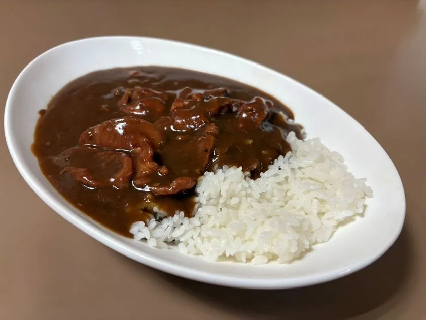 白い楕円皿に、濃いブラウンのラムカレーと白いライスが盛り付け