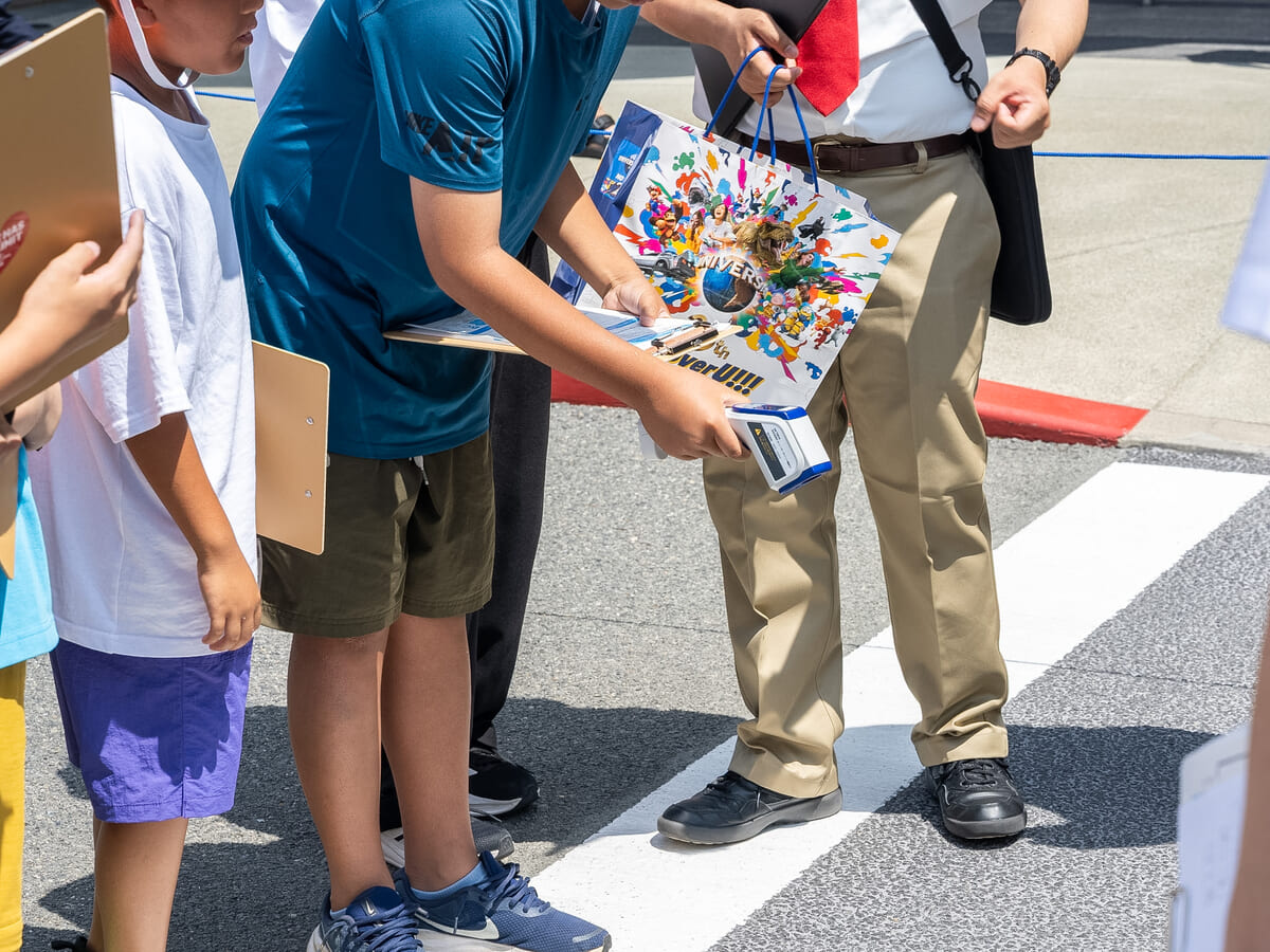 子どもがワークシートと温度計を手に地面の温度を計測する様子