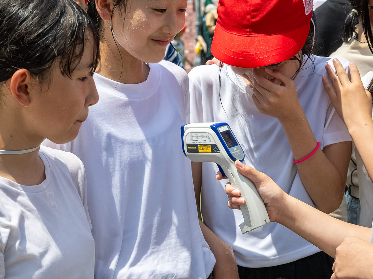 子どもたちが赤外線温度計で地面の温度を計測する様子