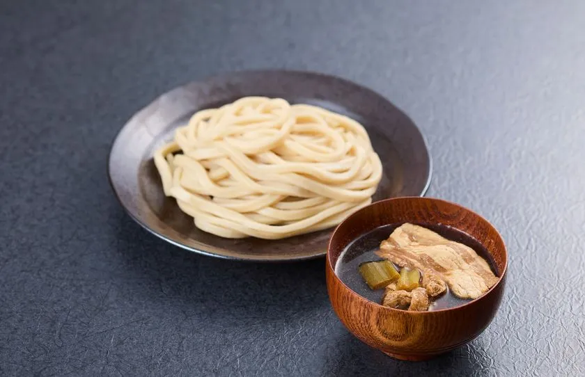 黒い皿に盛られた太めのうどんと