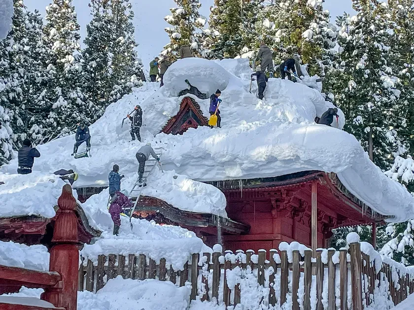 雪に覆われた神社建築の除雪作業