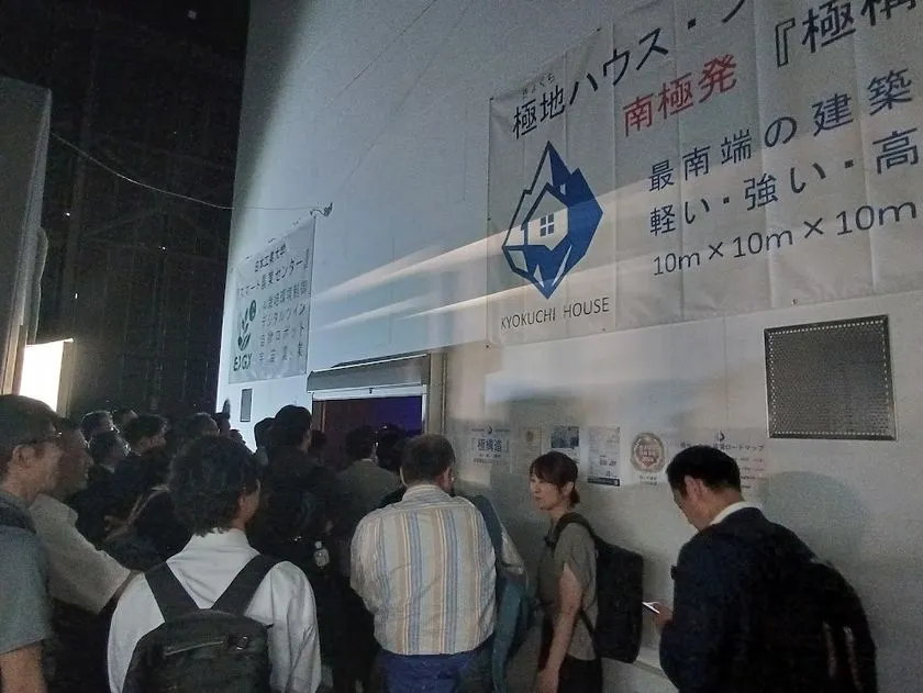 ロゴ掲示された施設入口と見学者