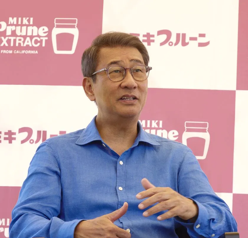 ミキプルーン背景前で語る中井貴一さん