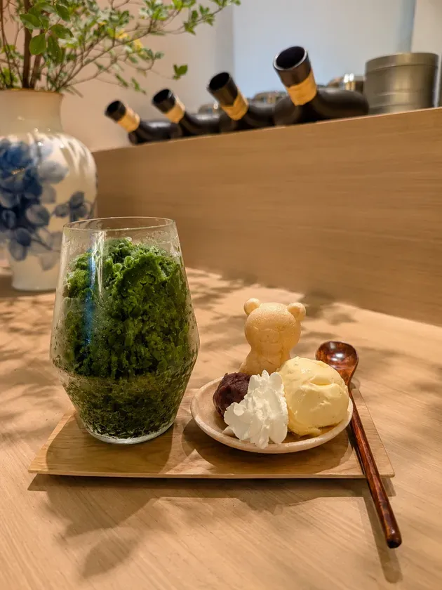 木製トレーに、濃い緑色の抹茶かき氷と別添えのあんこ