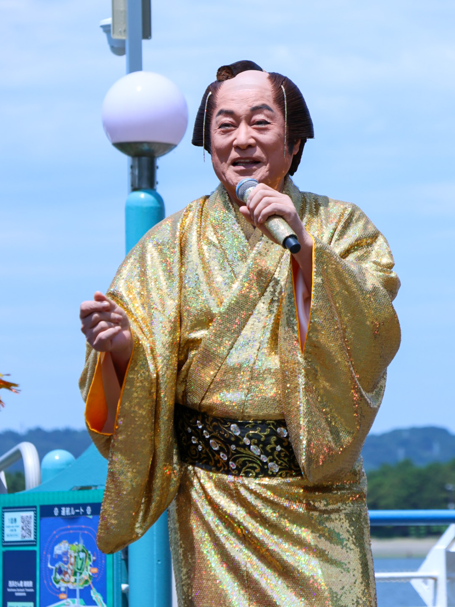 金色の着物姿でマイクを手に話す松平健さん