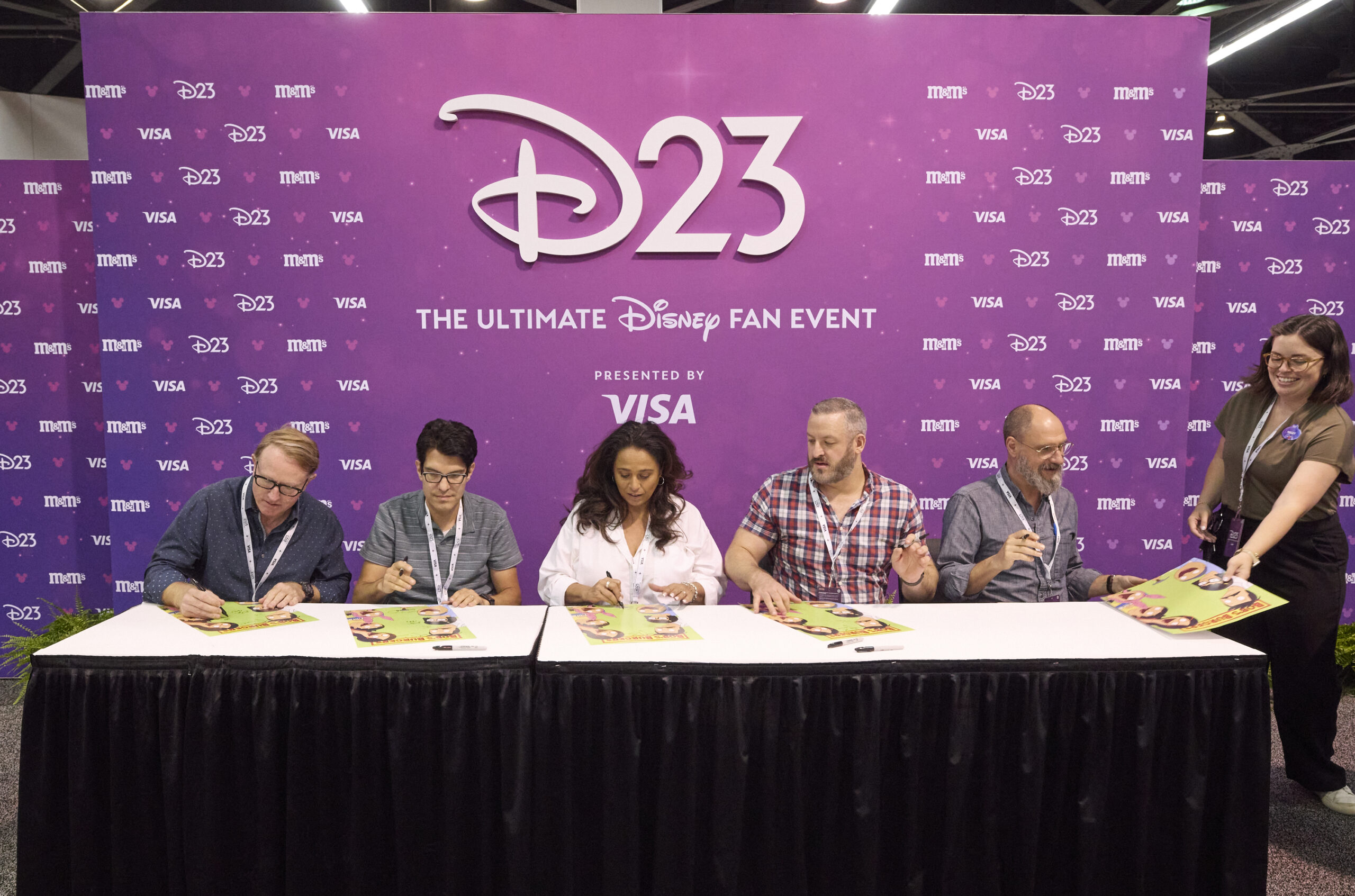 テーブルで色紙にサインする5人とD23のスタッフ