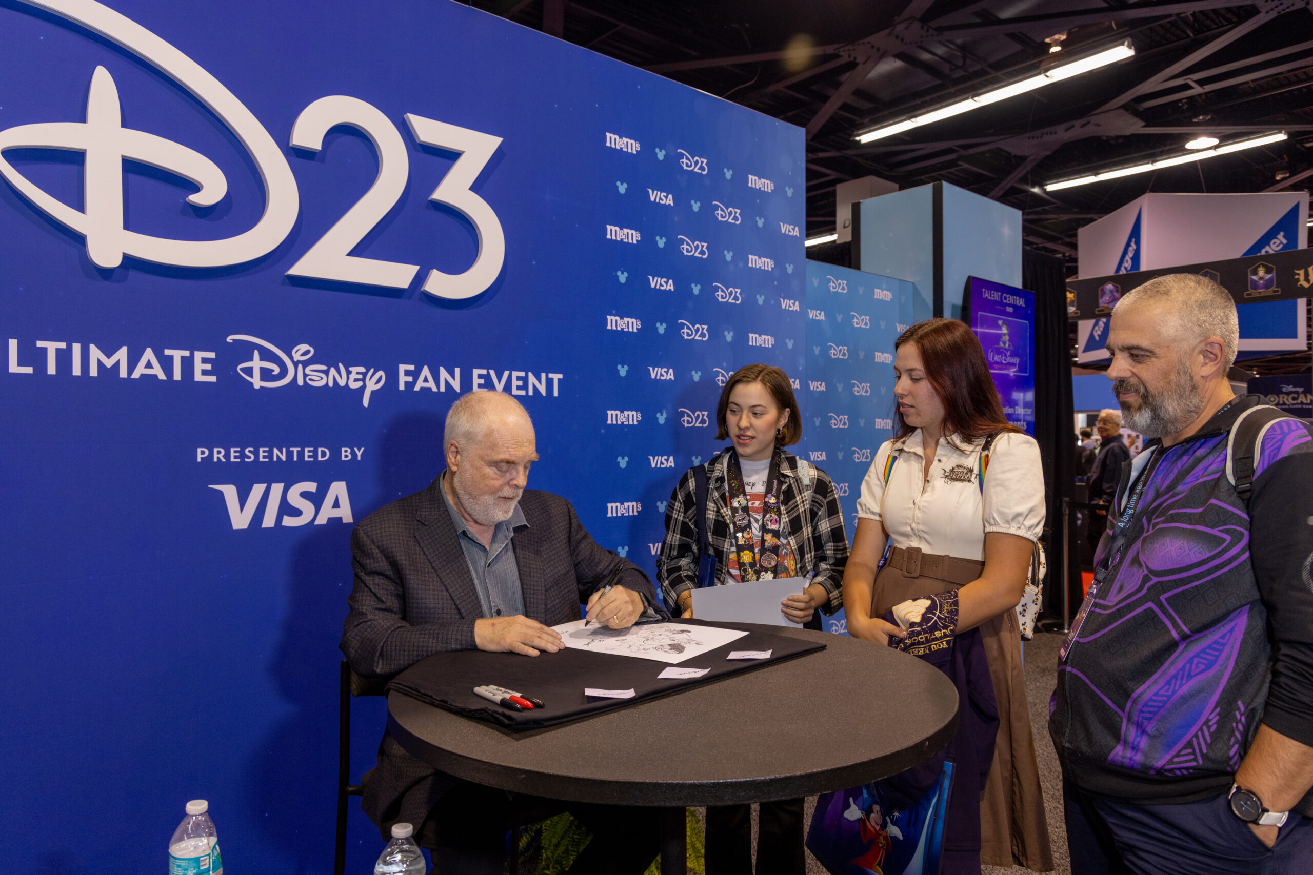 D23のバックドロップを背にサインを書き入れるロン・クレメンツ