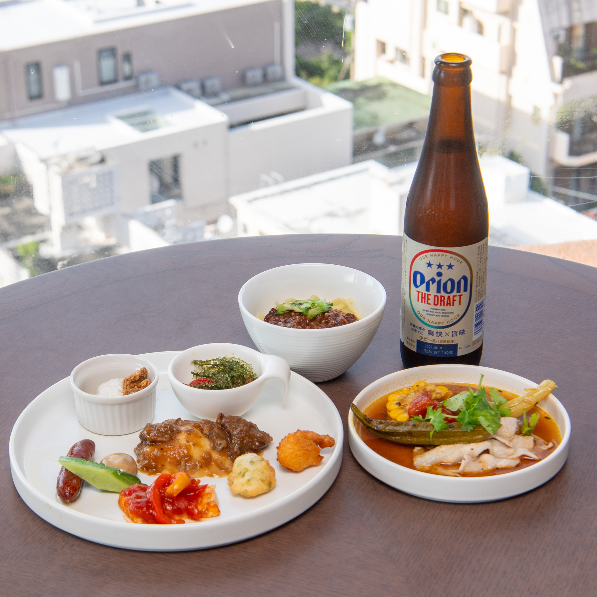 窓辺のテーブルに並べたディナータイムの料理とオリオンビール