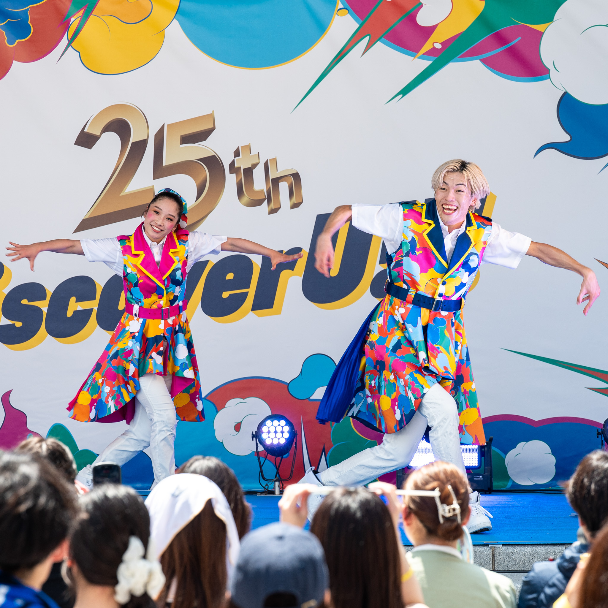 「25th Discover U!!!」のバナー前でポーズを取るエンターテイナー