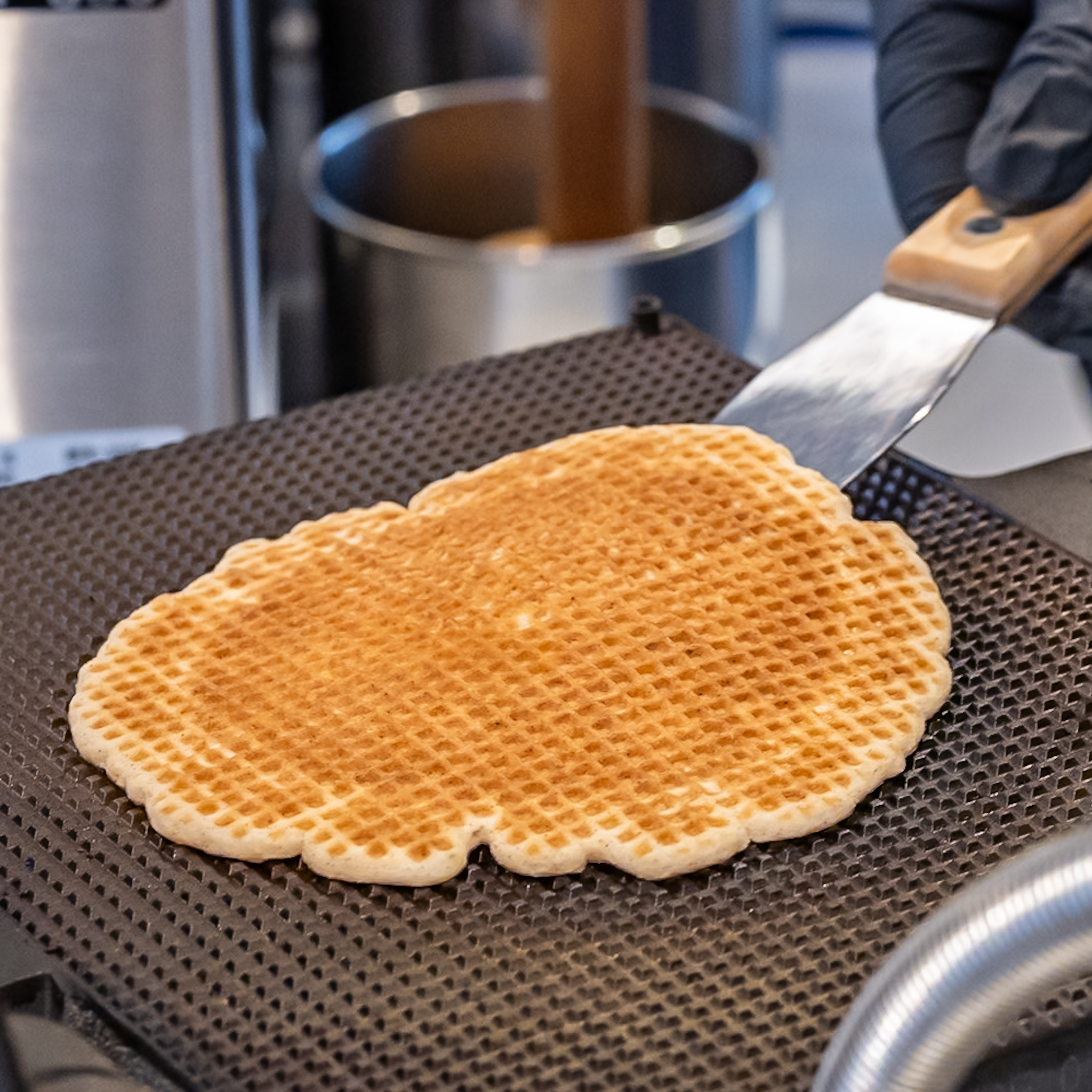 鉄板から焼きたてのワッフル生地をヘラで持ち上げる様子