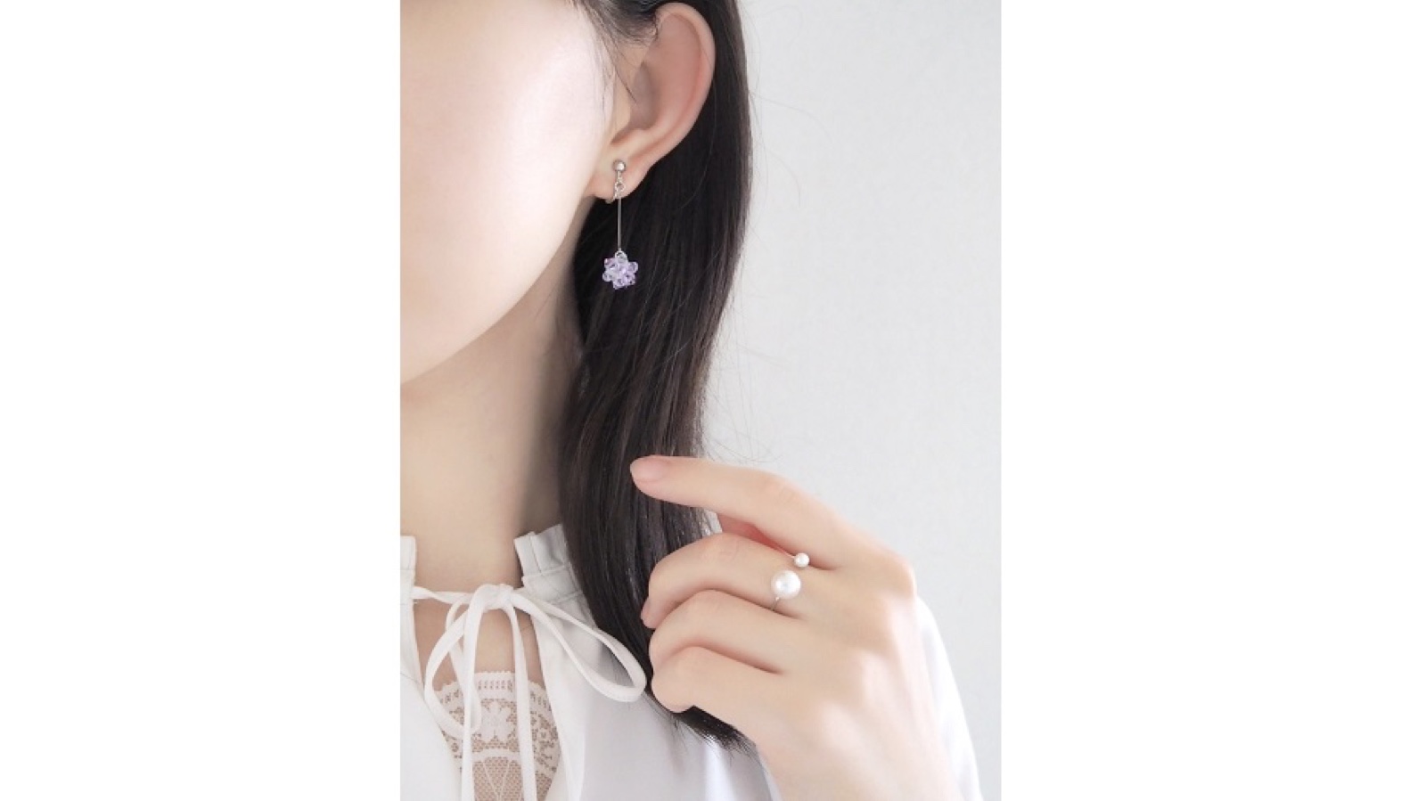 紫の花をかたどったピアスとパールのリングの着用例
