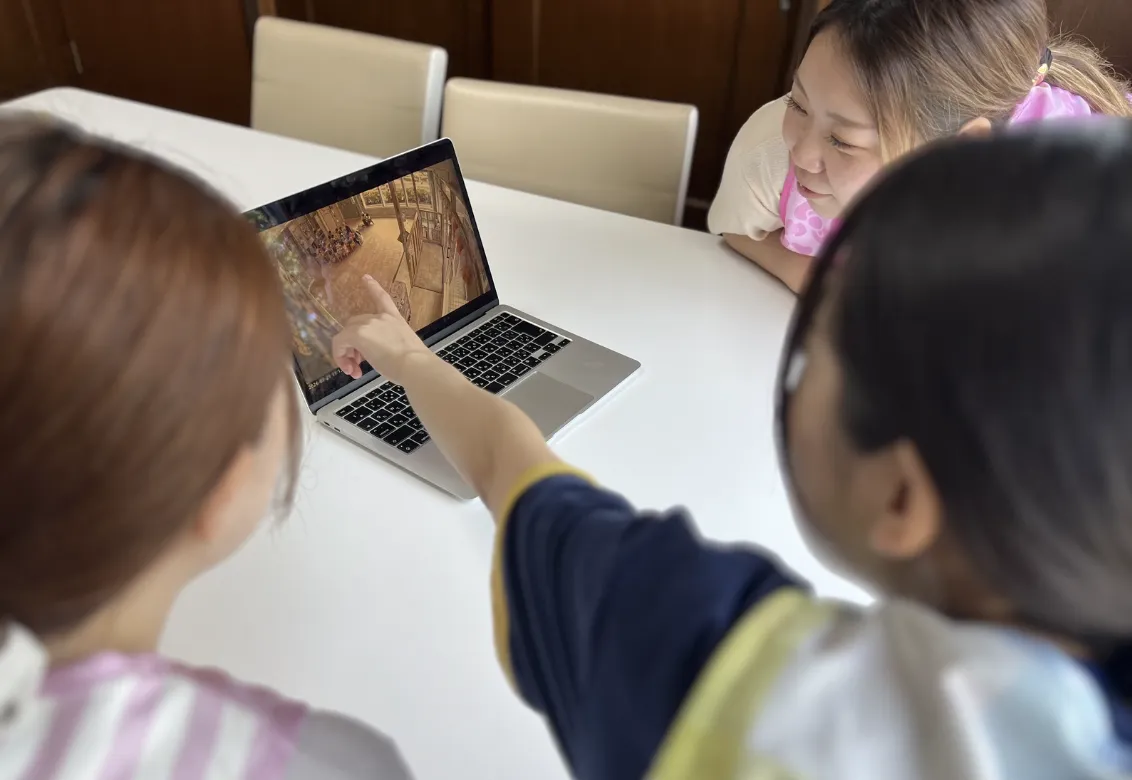 ノートパソコンの画面を指さす子ども