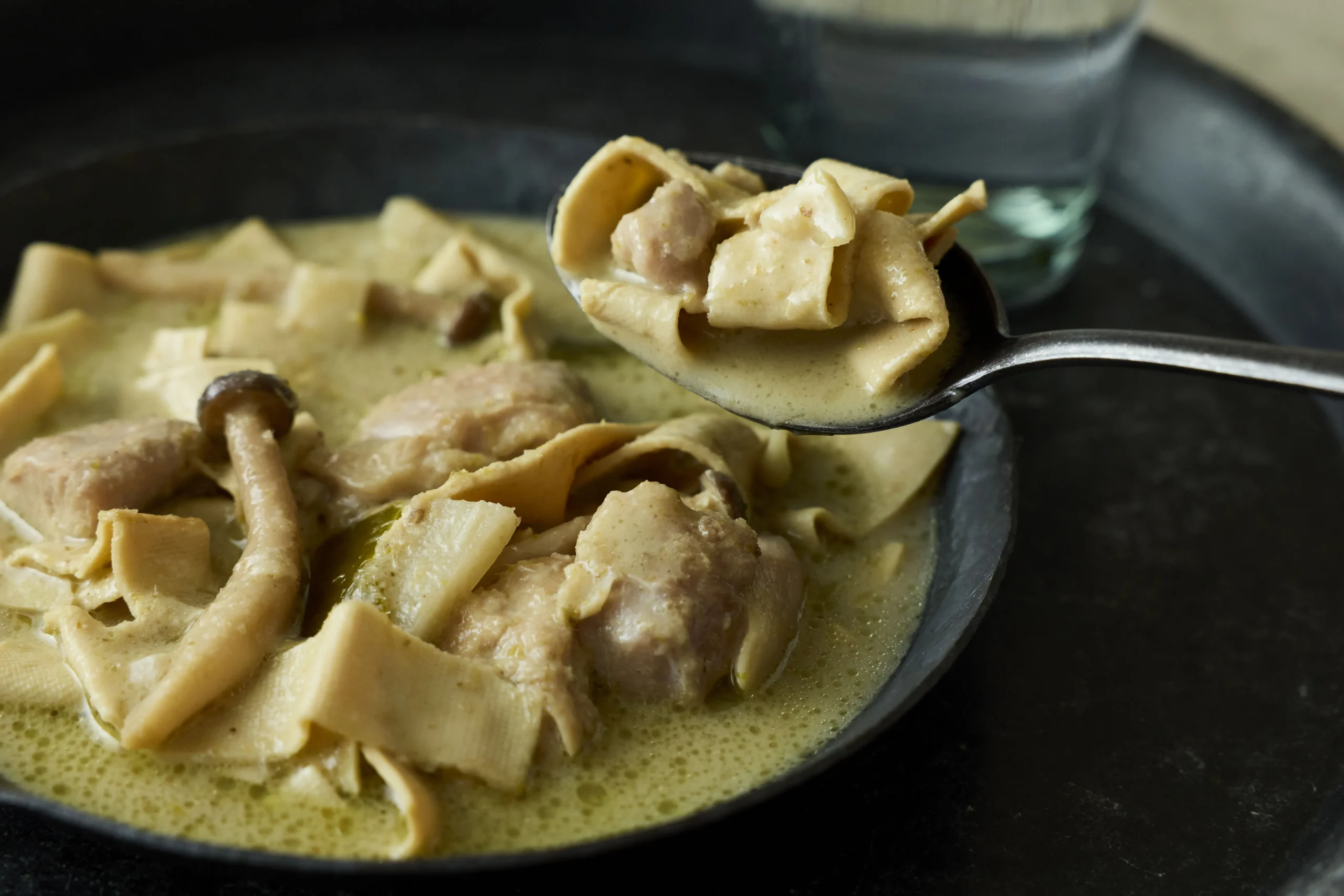 黒い深皿に盛られたグリーンカレーとスプーンですくう豆腐干