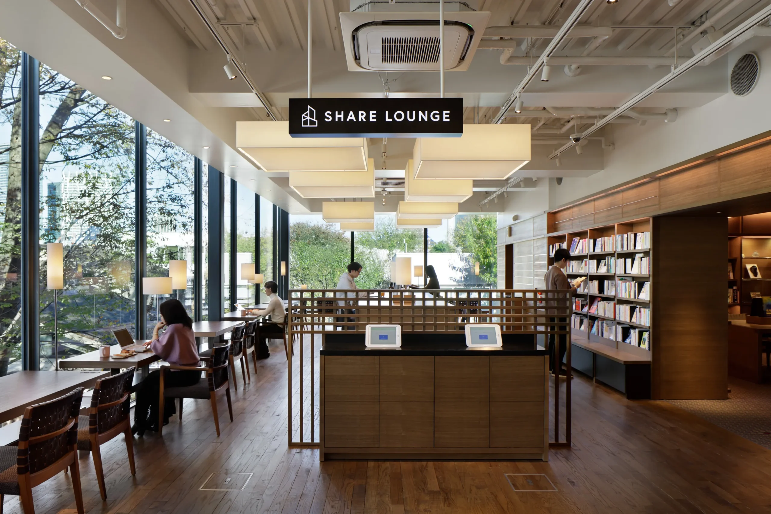 大きな窓と木製書棚を備えたSHARE LOUNGEの内観