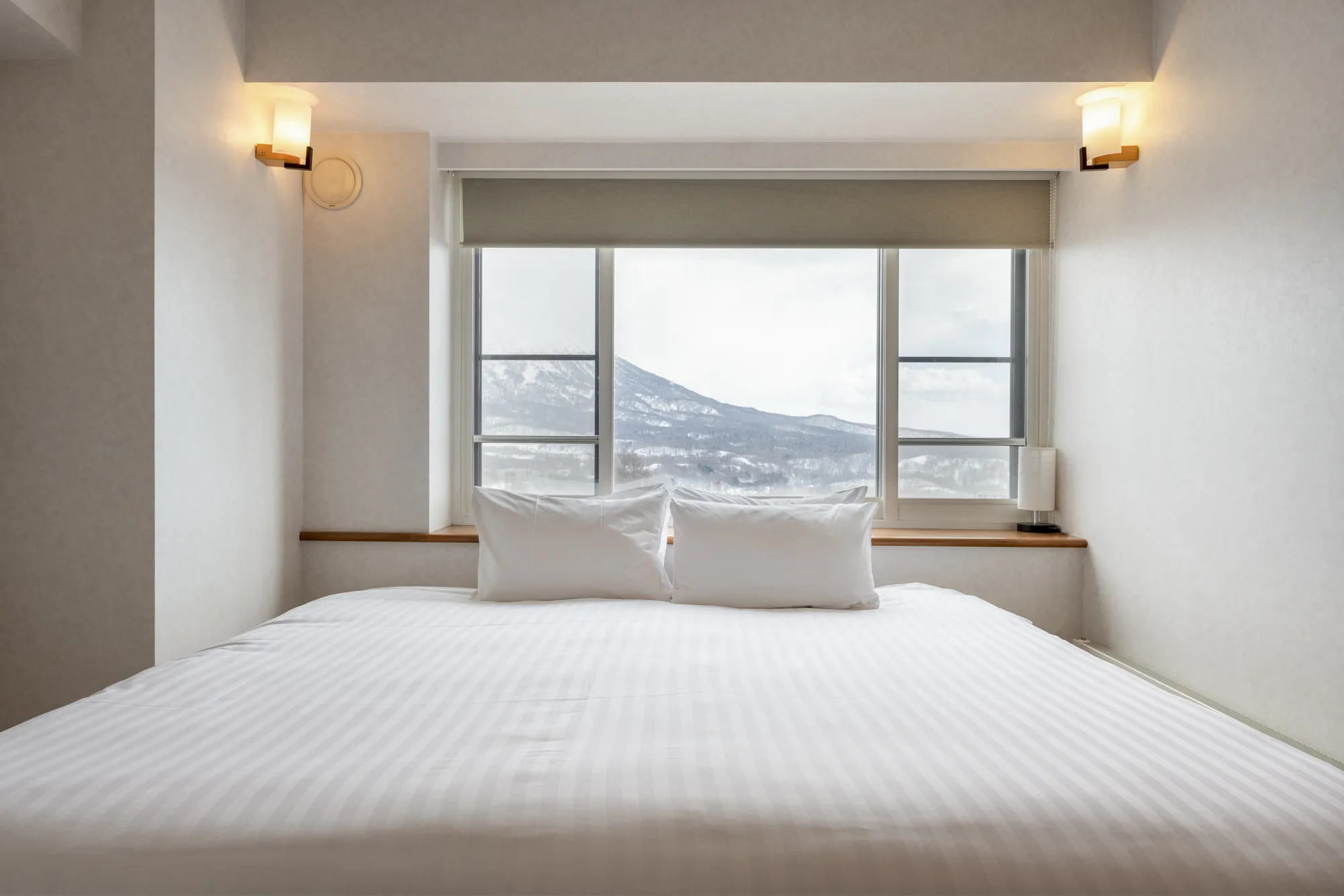 雪をかぶった山並みを望む寝室のベッド