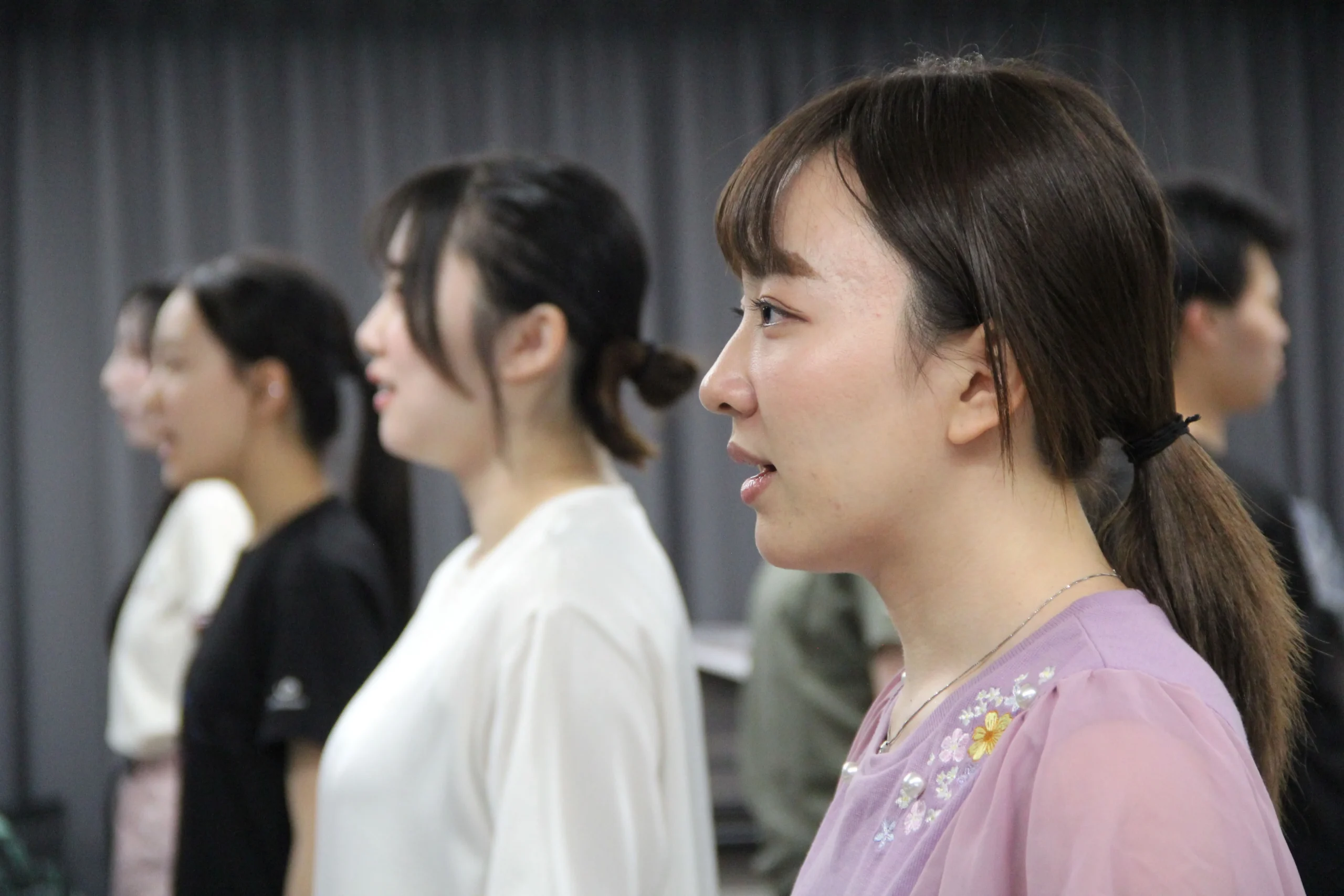 横一列に並び発声練習をする女性アンサンブル