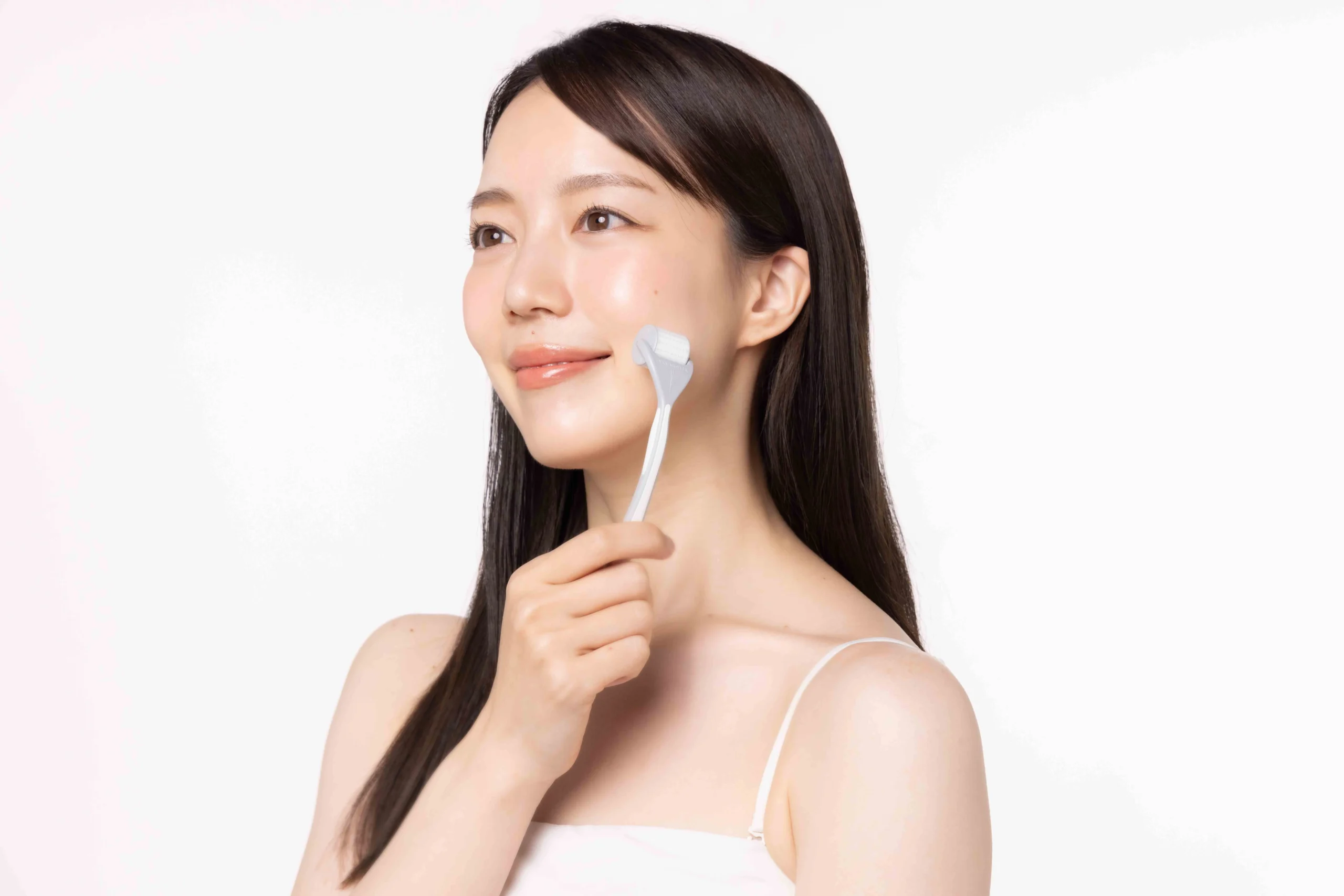 頬にダーマローラー本体を当てる女性