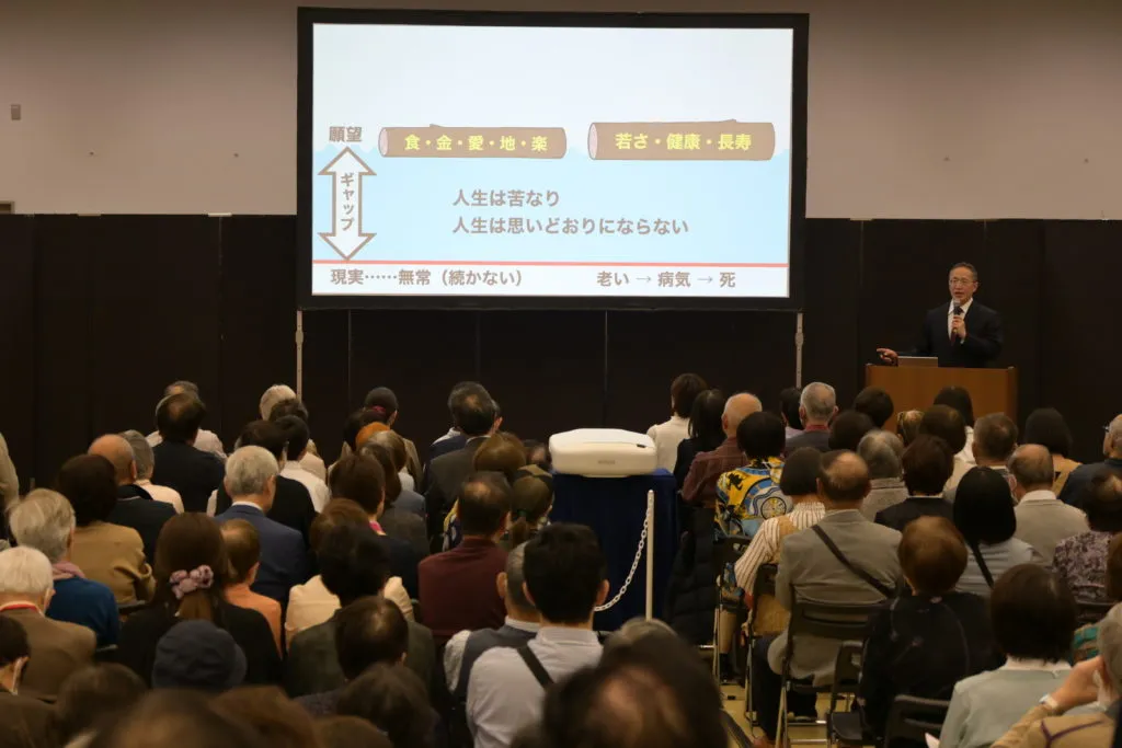 メイン講演で語りかける講師とスクリーンの解説スライド