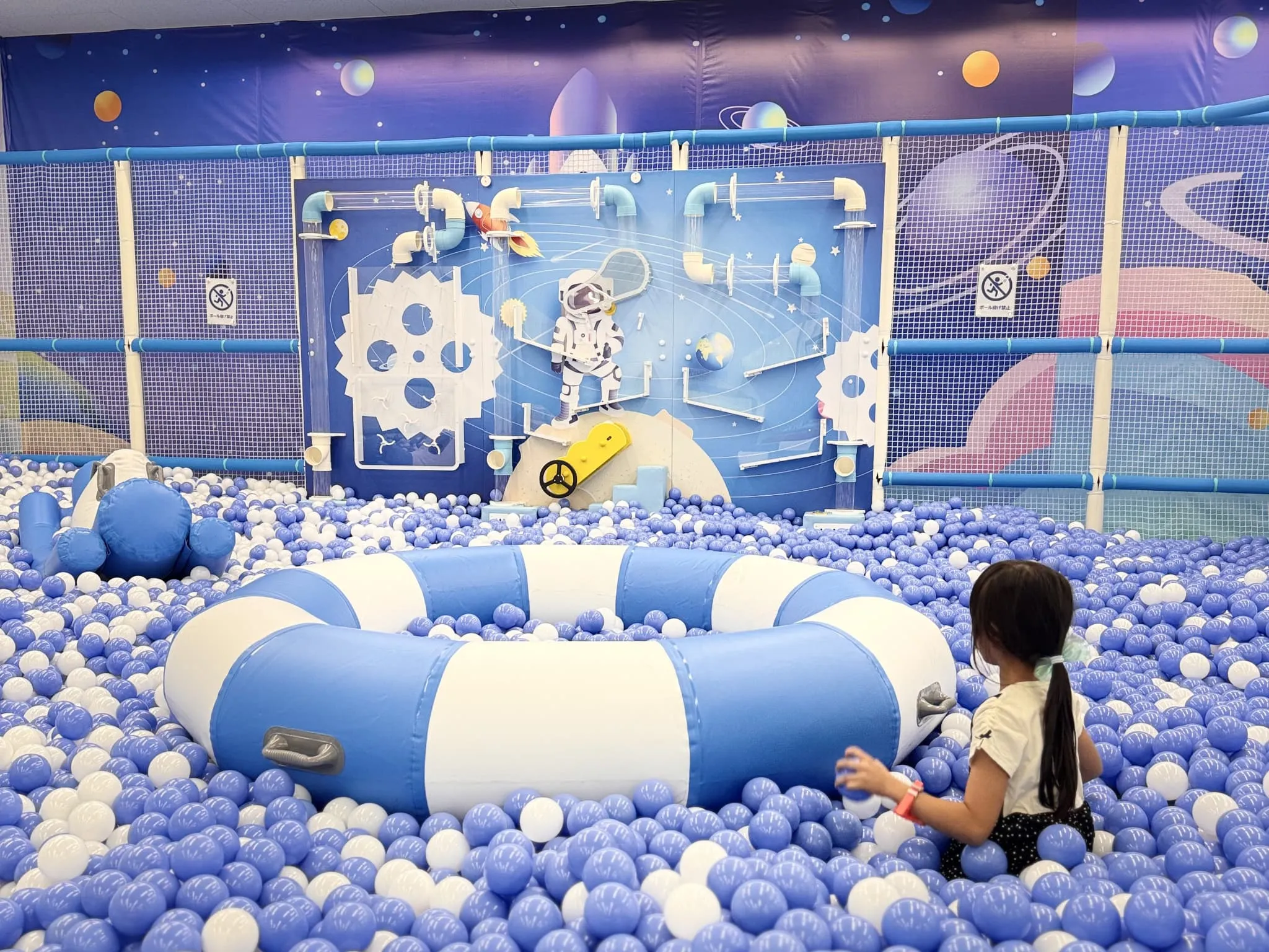 宇宙テーマのボールプールで遊ぶ女の子