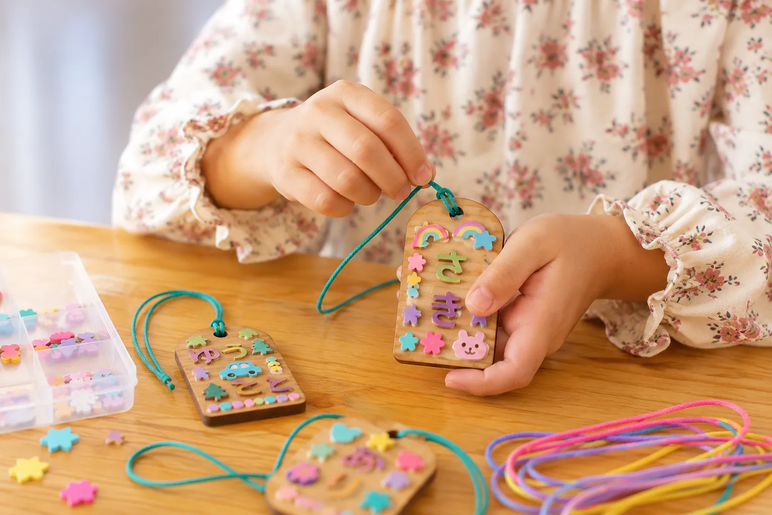 木製ネームタグにひらがなパーツを貼り付ける子ども