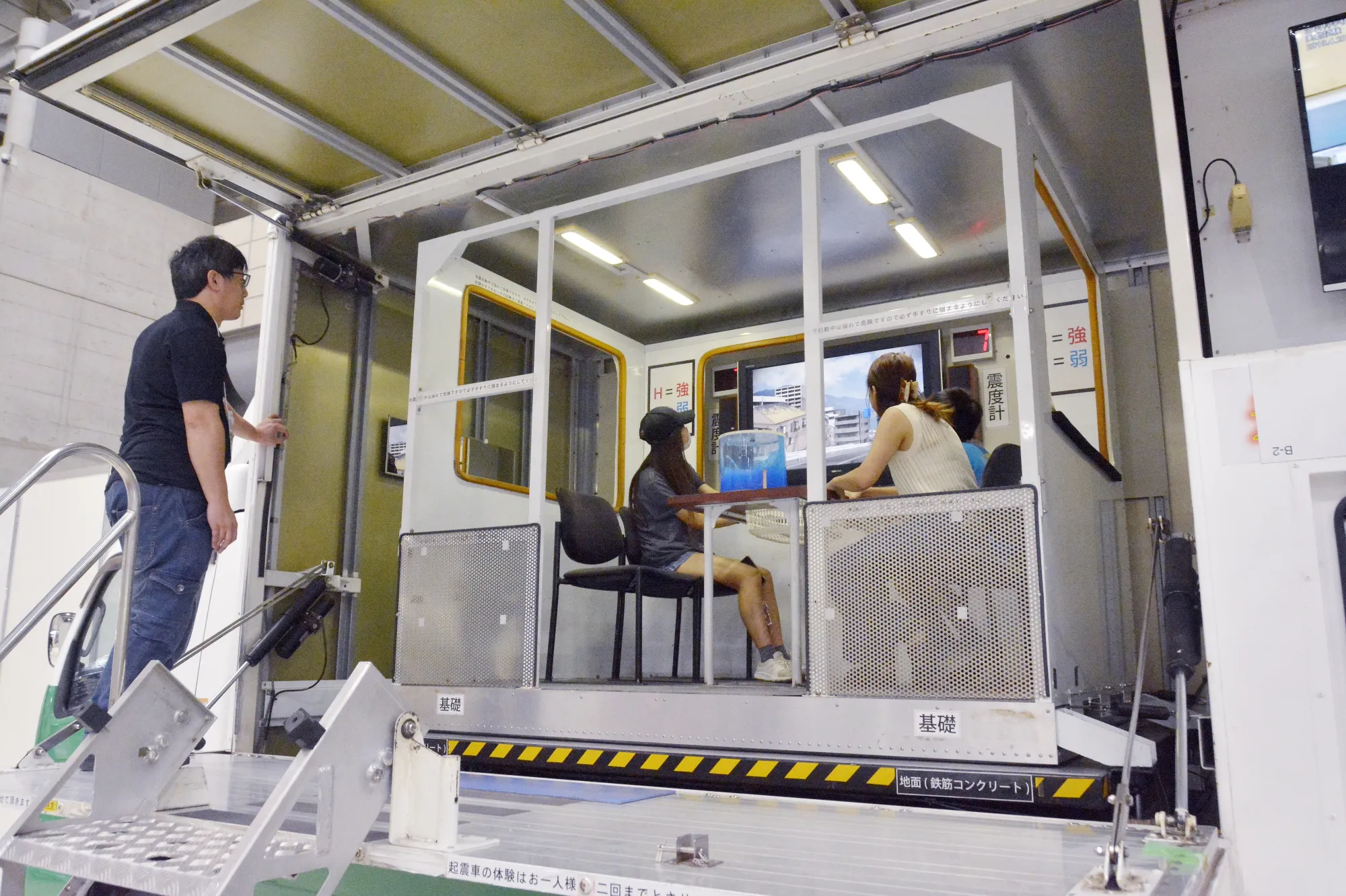 起震車の車内で地震の揺れを体験する来場者